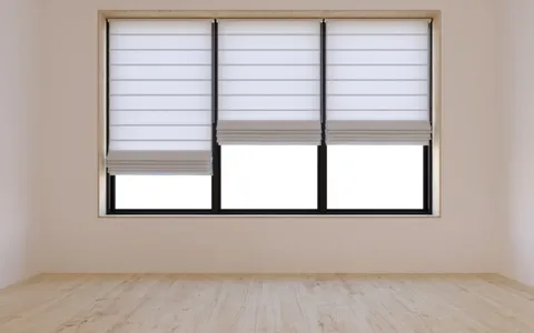 Bele rolo zavese na prozoru prazne sobe